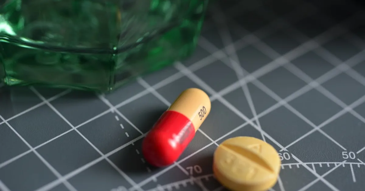 Red and yellow medication pill on green glass bottle