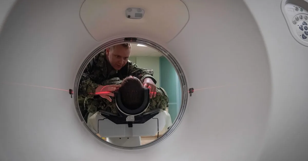 Technician positioning a patient in a CT scanner in a hospital radiology suite