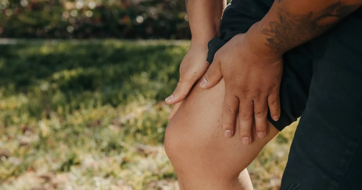 Person holding their knee indicating leg pain, a common symptom of deep vein thrombosis