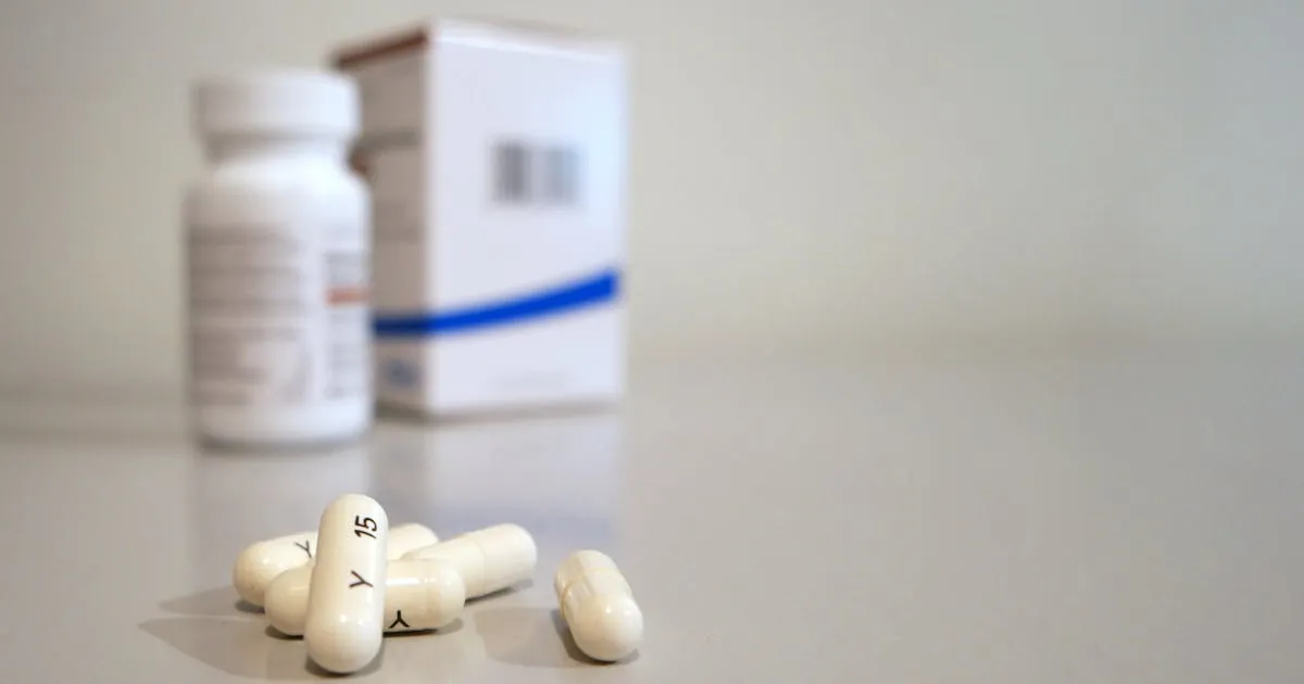 White medication capsules with medicine bottle, representing anticoagulant therapy